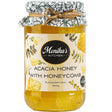 A jar of pure acacia honey with a piece of fresh cut raw honeycomb.