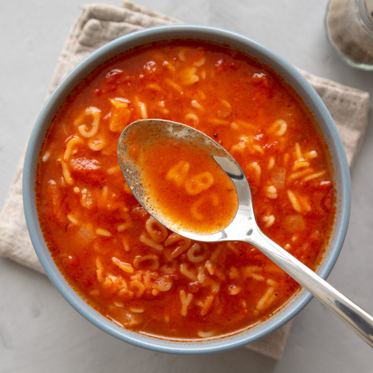 A bowl of alphabet spaghetti tomato soup with letter shaped pasta macaroni noodles.