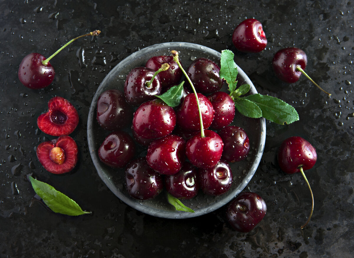 Fresh black cherry fruit on a dark background.
