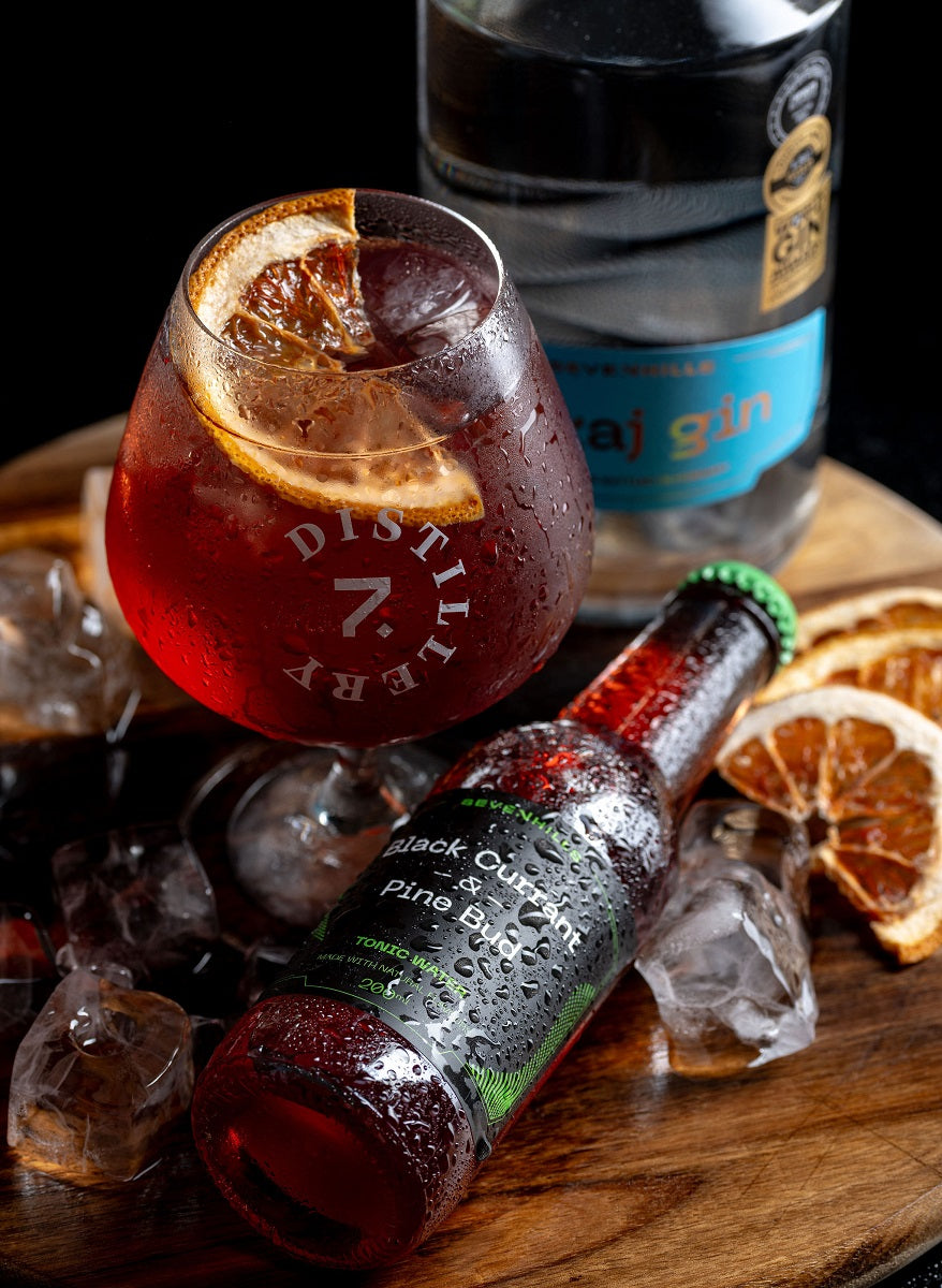 A bottle and a glass of tonic water made with blackcurrant and pine buds.