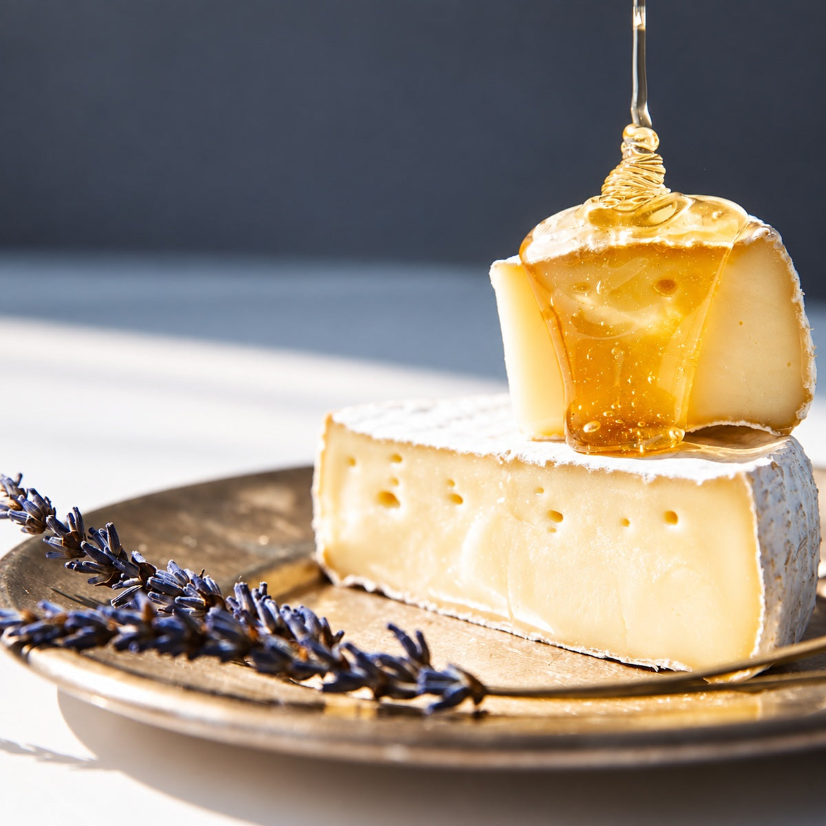 A piece of Camembert cheese with a drizzle of golden honey on a plate.