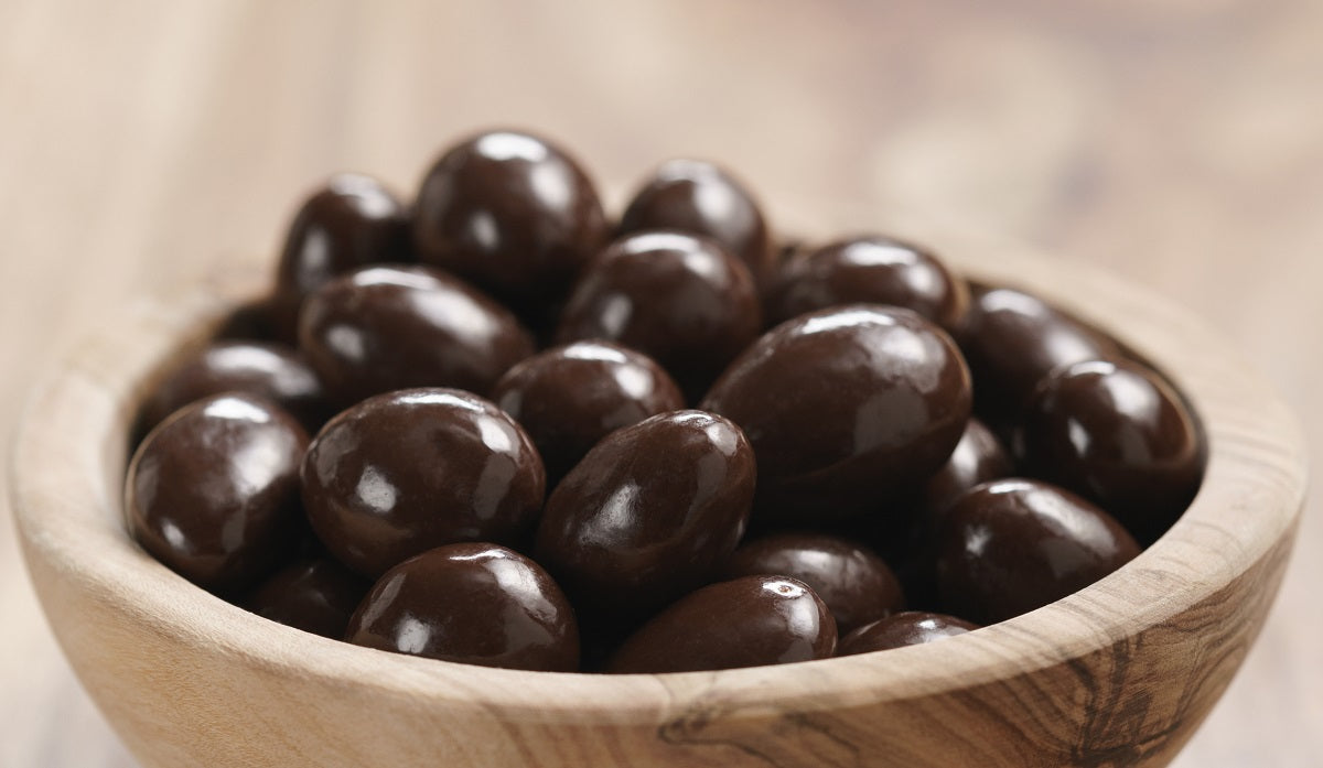 A bowl of roasted almonds covered in dark chocolate coating.
