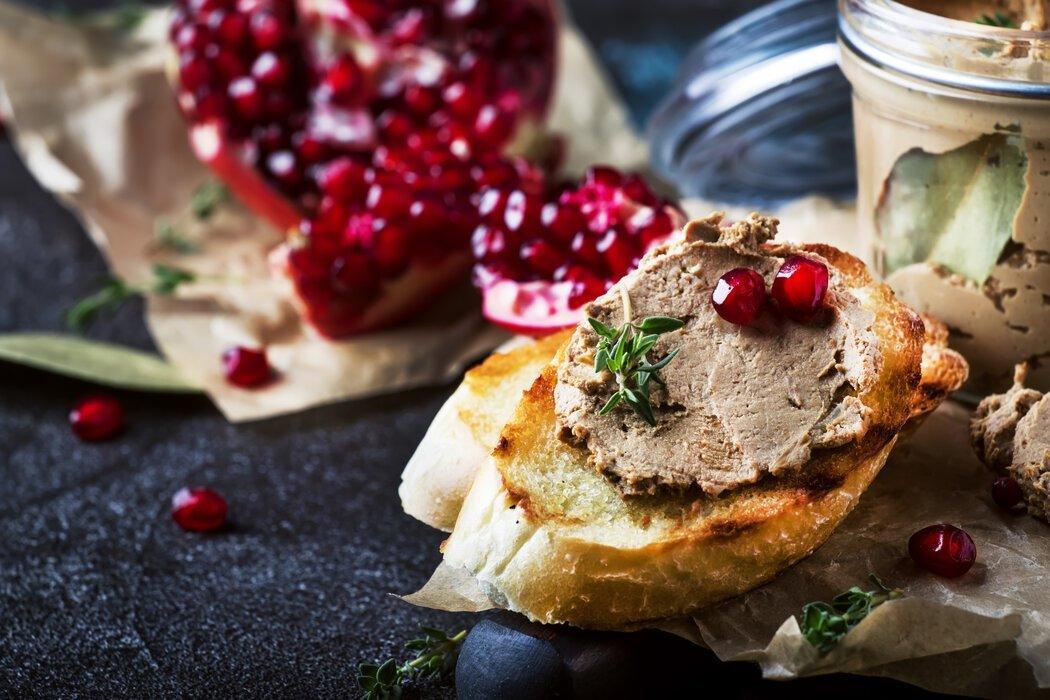 Goose liver pate de foie gras spread on toast with pomegranate seeds.