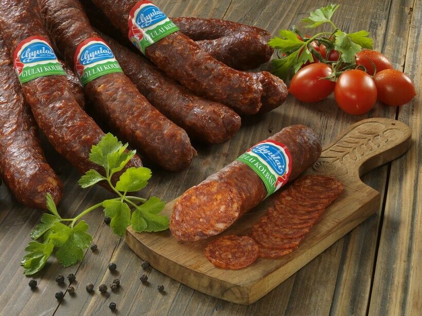 Slices of Gyulai kolbász, a traditional Hungarian smoked pork sausage, with tomatoes on a chopping board.