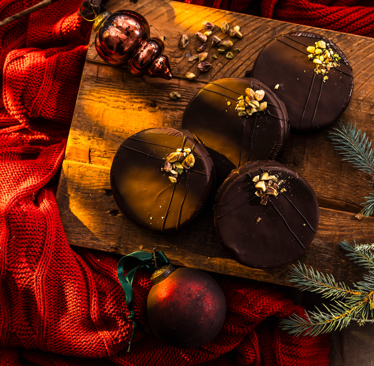 Ischler chocolate cookies on a wooden chopping board with Christmas decorations.