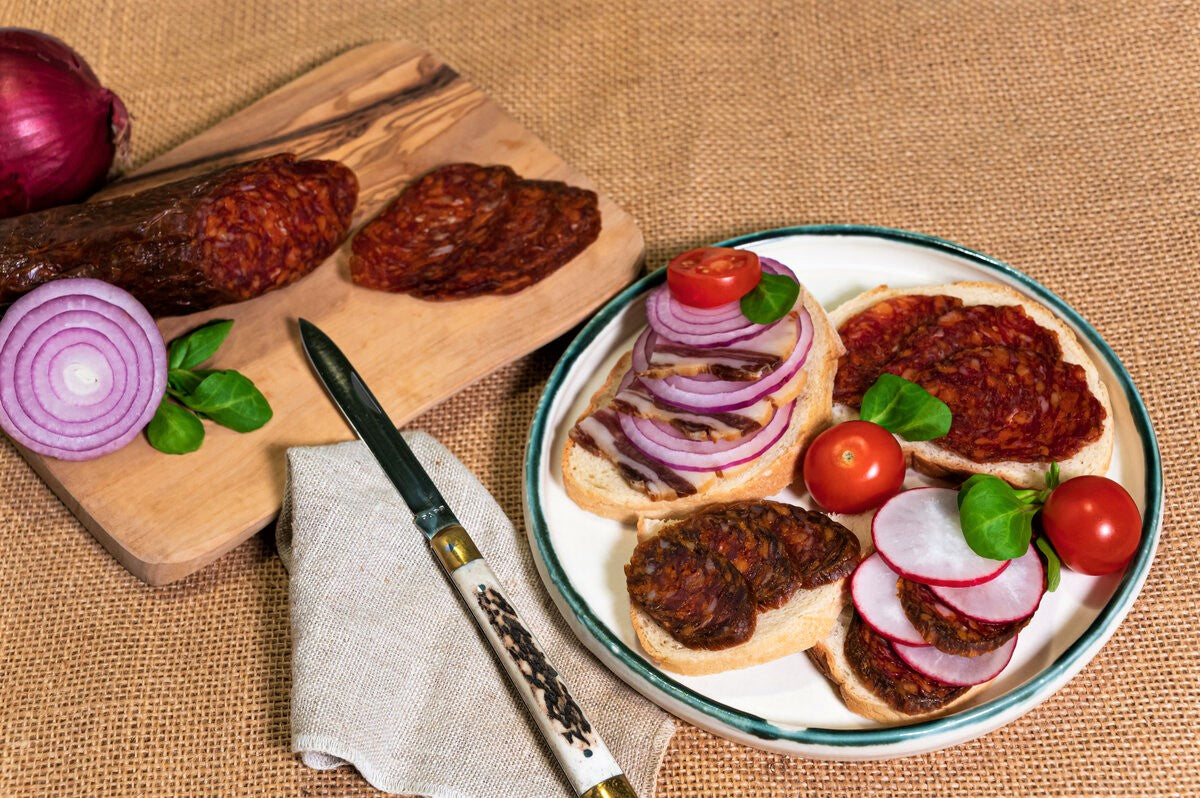 An open faced sandwich recipe with ingredients including mangalitza salami, radish, red onion and tomatoes.