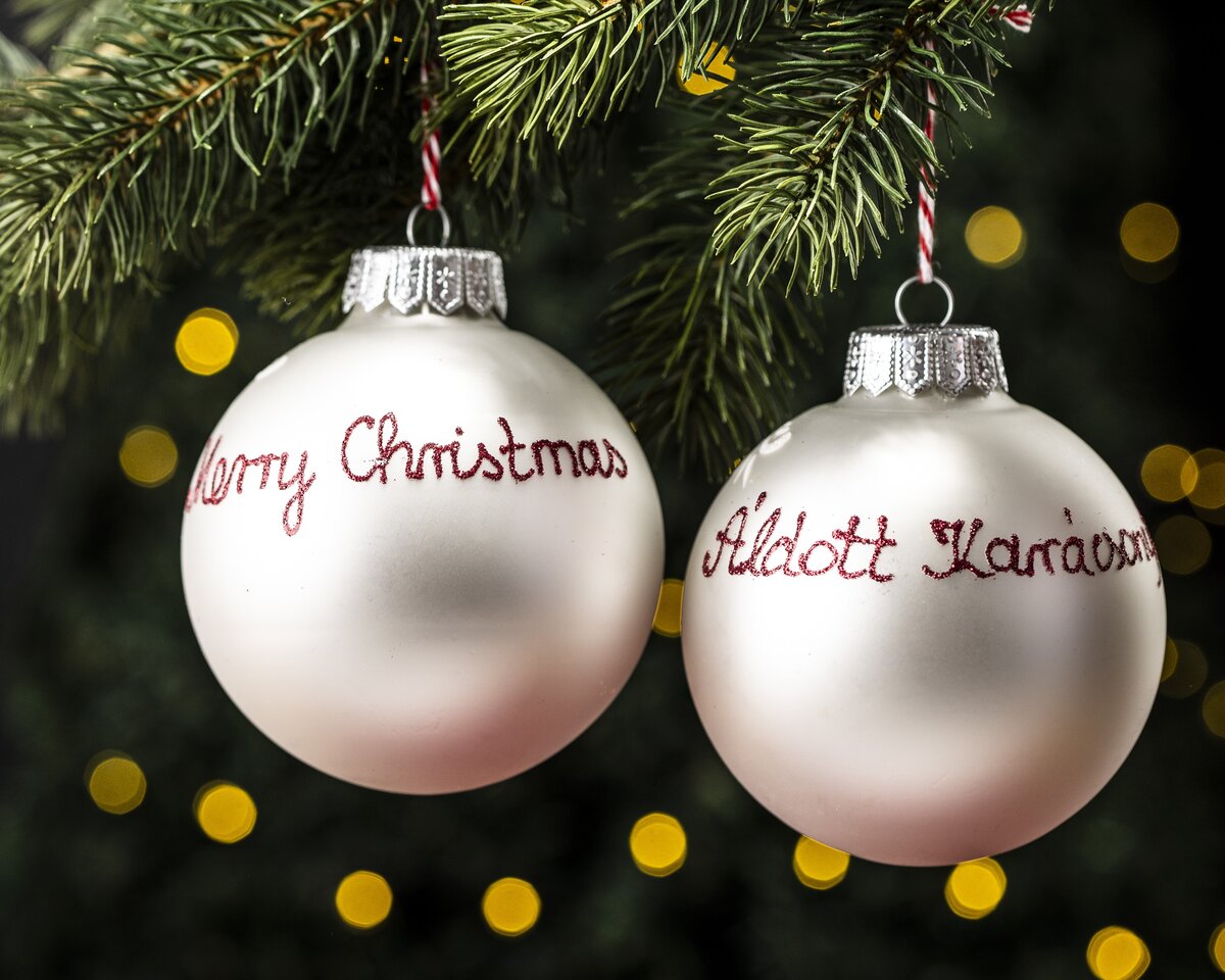 A pair of English and Hungarian Christmas bauble decorations wishing a Merry Christmas and Áldott Karácsonyt.
