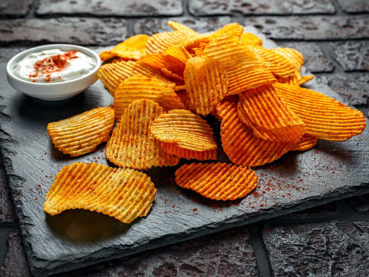 Crunchy potato crisps seasoned with paprika powder and served with a sour cream dip.