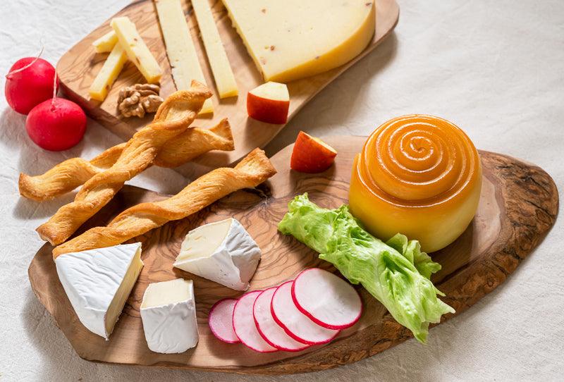 An artisan parenica smoked cheese on a wooden board with crackers, radish and apple slices.