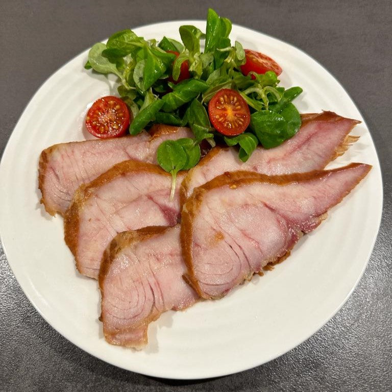 Smoked sturgeon fillets from premium fish meat with salad on a plate.