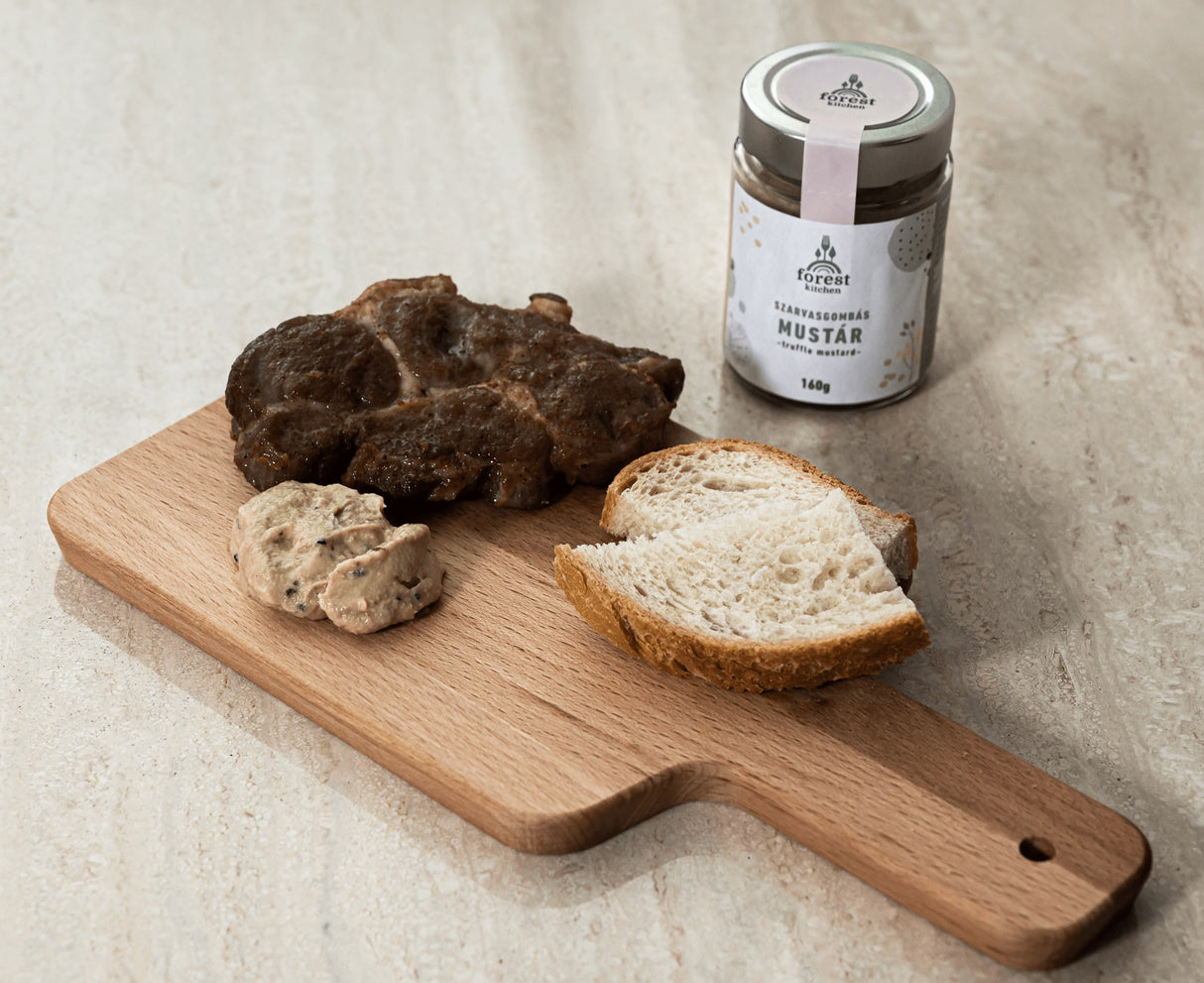A jar of truffle mustard made with black summer truffles next to steak and bread.