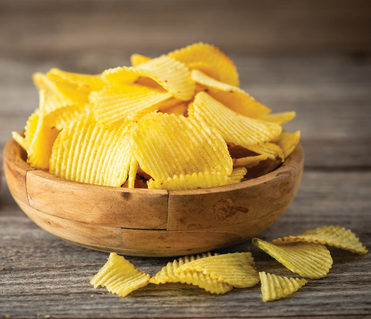 Crunchy potato crisps in a wooden bowl seasoned with real black truffles.