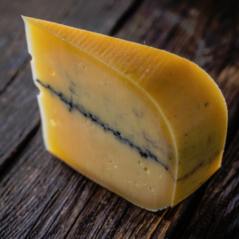 A wedge of gourmet cheese with an ash line in the middle.