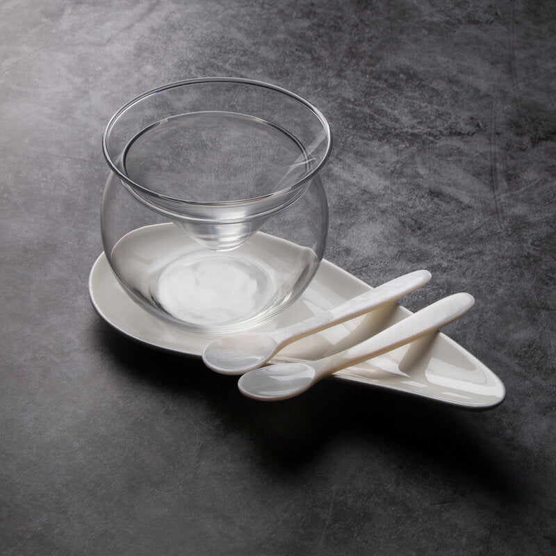 A luxury caviar serving set with a glass server dish, ceramic plate and the best mother-of-pearl spoons.