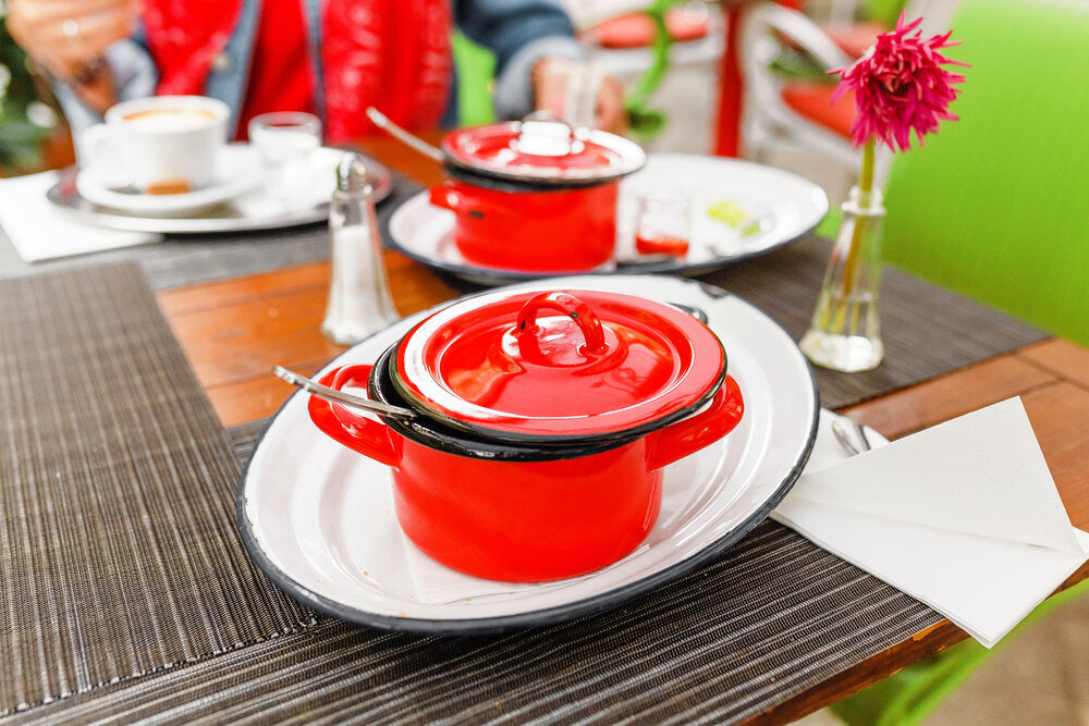 A red enamel stock pot with a lid, this traditional cookware is best for cooking soup.