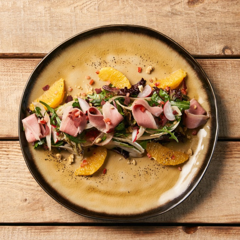 A fine dining starter dish with slices of smoked duck breast charcuterie.