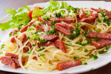 A salami pasta recipe with spaghetti, crispy salami slices and grated cheese.