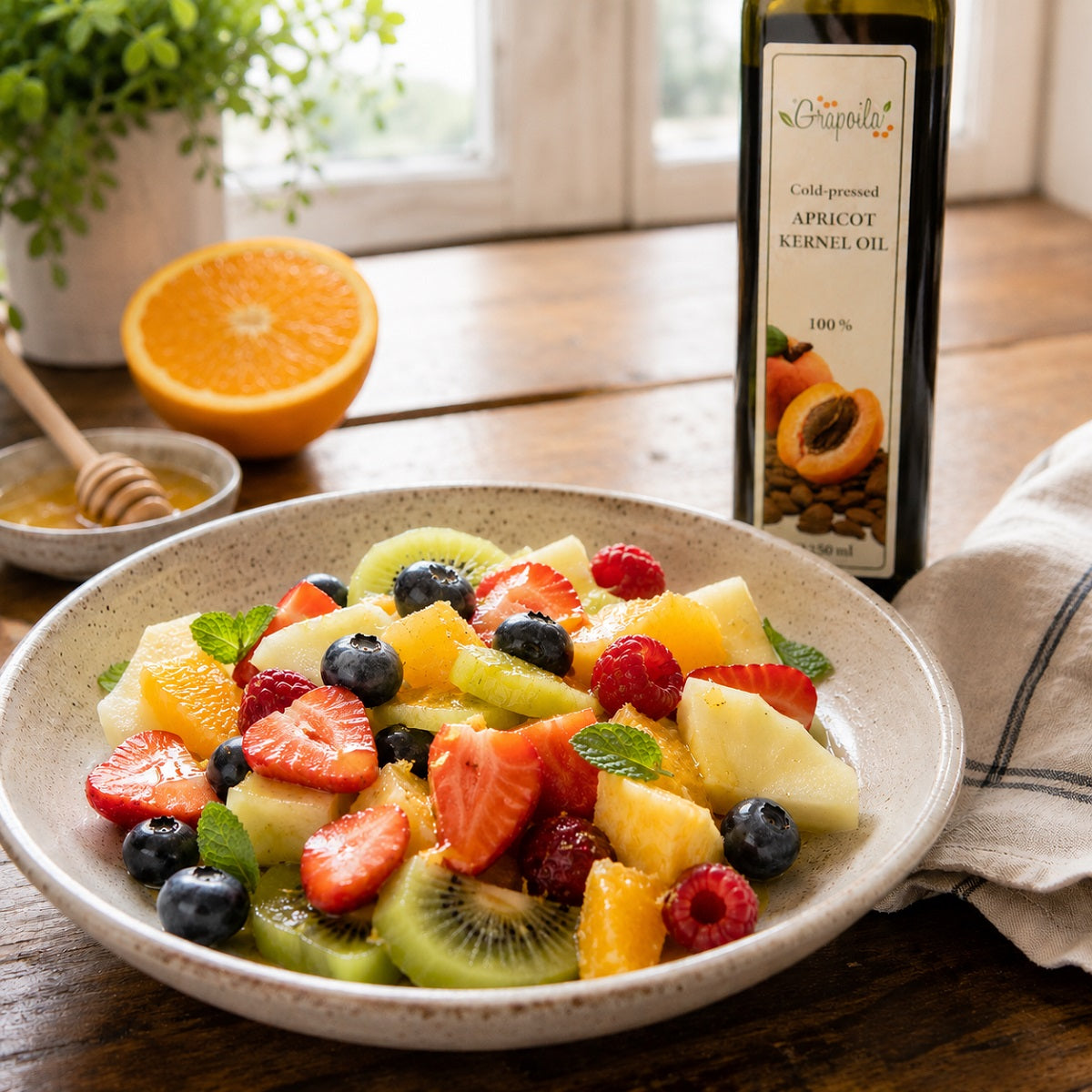 Bowl of fruit salad with a drizzle of apricot kernel oil and a bottle in the background.