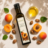 Apricot oil in a jar, with fresh apricots and apricot kernels on a light background.