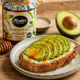 Avocado toast on a plate with Monika's Kitchen chestnut honey jar and an avocado in the background.