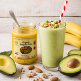 Avocado smoothie with a jar of organic propolis honey, avocado, and bananas on a wooden surface.