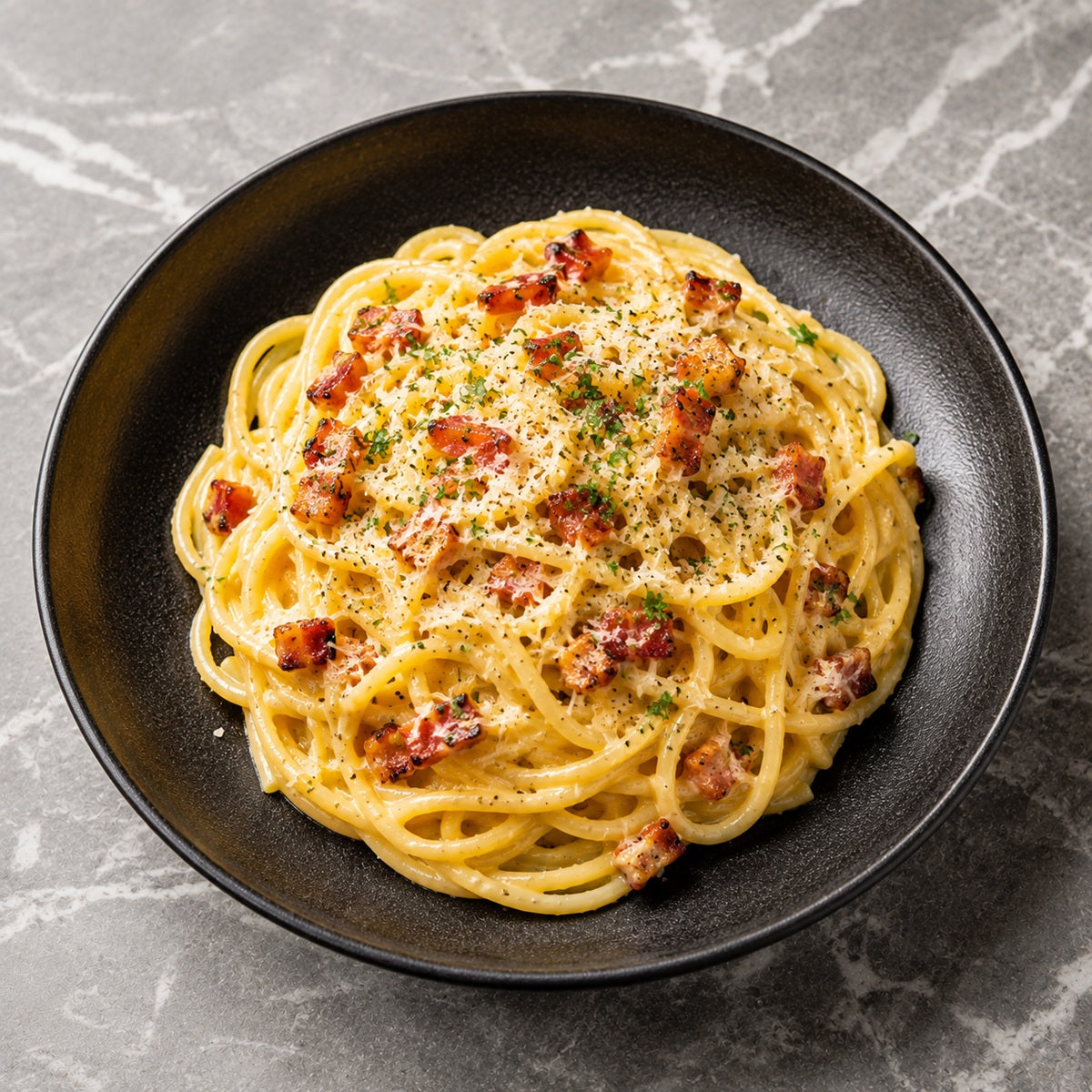 Spaghetti carbonara with bacon bits and parmesan cheese in a black bowl on a grey marble background