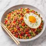 Bacon fried rice with vegetables and a fried egg on a grey plate with chopsticks.