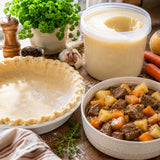 Unbaked pie crust, container of beef tallow, and bowl of pie filling on a wooden surface.