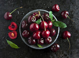Fresh black cherry fruit on a dark background.