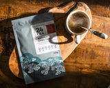 A steaming cup of Tartary buckwheat tea with a pack of buckwheat tea on the side.