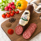 Buffalo salami is a pork-free salami made with buffalo meat, on a wooden board with vegetables and spices.