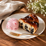 Poppy seed cake with strawberry ice cream on a plate with a fork, on a wooden table with flowers.
