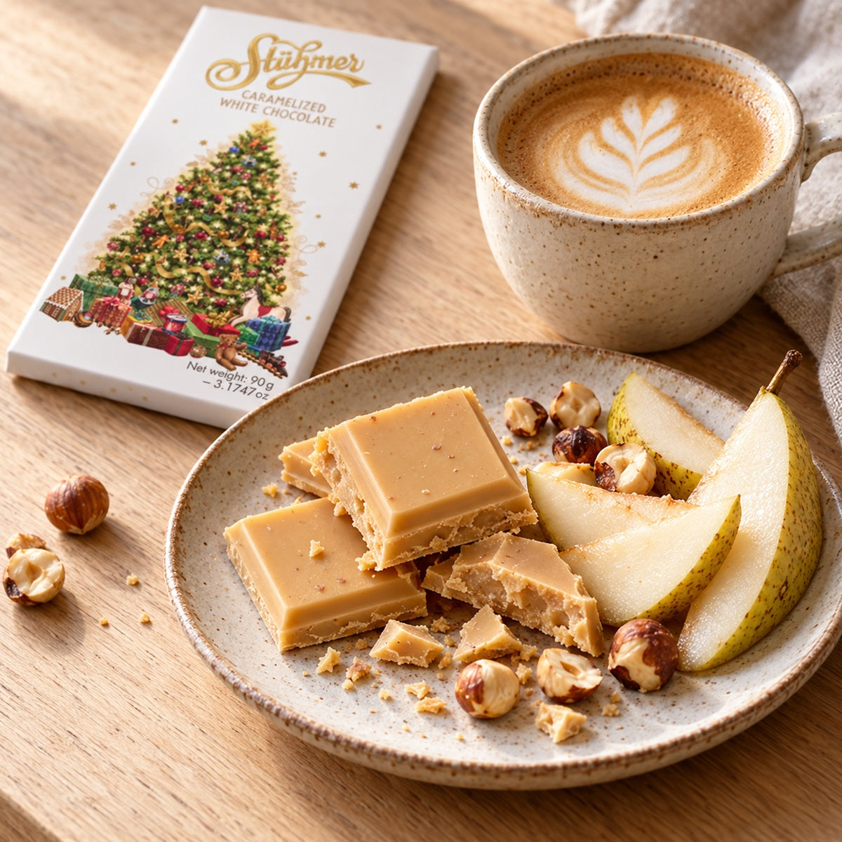 A plate of caramelised white chocolate bars with sliced pear and hazelnuts and a cup of latte with leaf latte art.