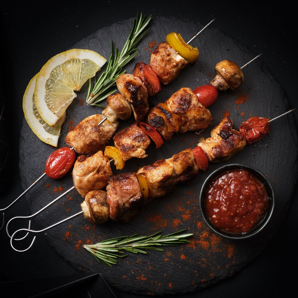 Skewers of grilled chicken with vegetables, accompanied by a bowl of BBQ Ketchup.