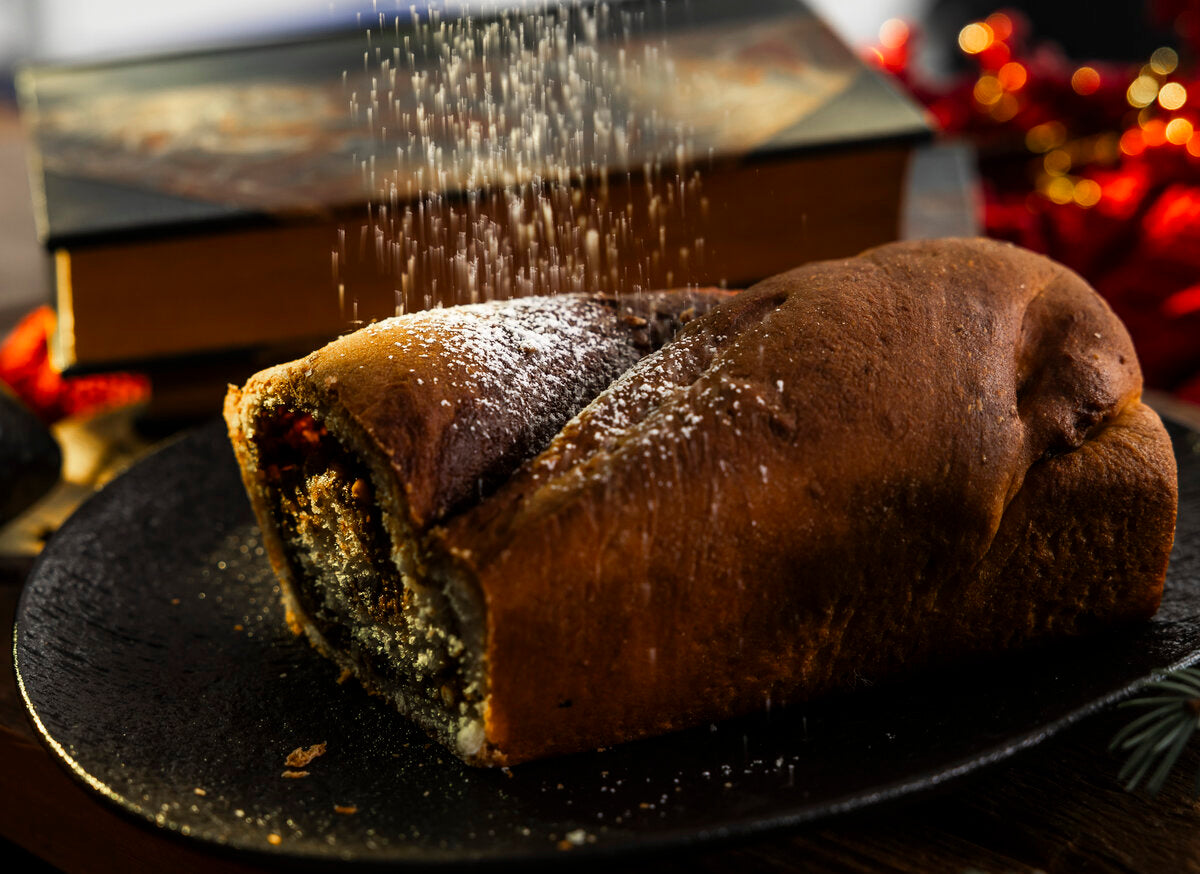 A chocolate babka being dusted with icing sugar.