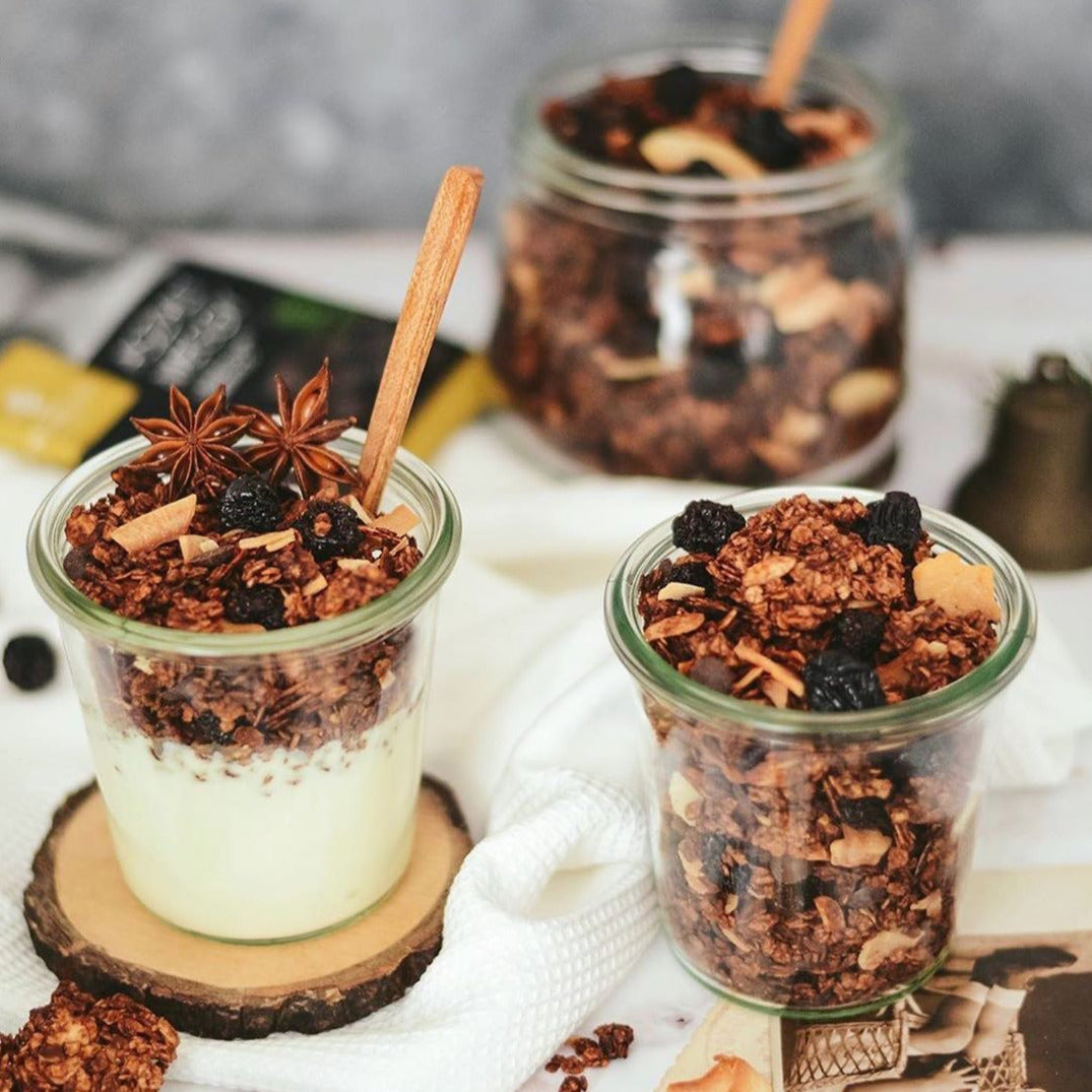 Cups of granola muesli and yoghurt topped with dried black cherries.
