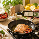 Person pouring grapeseed oil into a frying pan with salmon and cherry tomatoes.