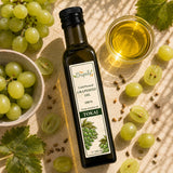 Bottle of cold-pressed grapeseed oil with green grapes and grape seeds on a light background.