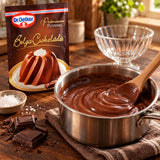 A saucepan of creamy chocolate pudding with a spoon on a countertop beside a package of Dr Oetker Chocolate Pudding Mix.