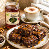 Brownies with caramel drizzle on a plate with a jar of organic pine honey and a cup of coffee.