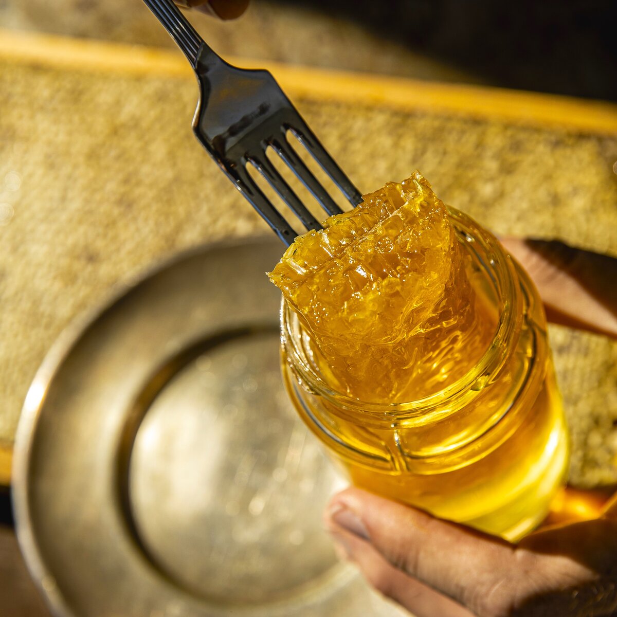 A piece of fresh bee honeycomb in a jar of honey for eating.