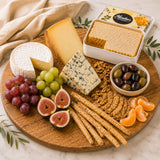 Wooden platter with assorted cheeses, raw honeycomb, fruits, and crackers on a marble surface.