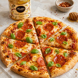 Pepperoni pizza with cheese and basil leaves on a stone surface, drizzled with hot honey.