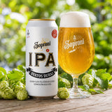 Soproni IPA beer can and glass with hops on a wooden surface.