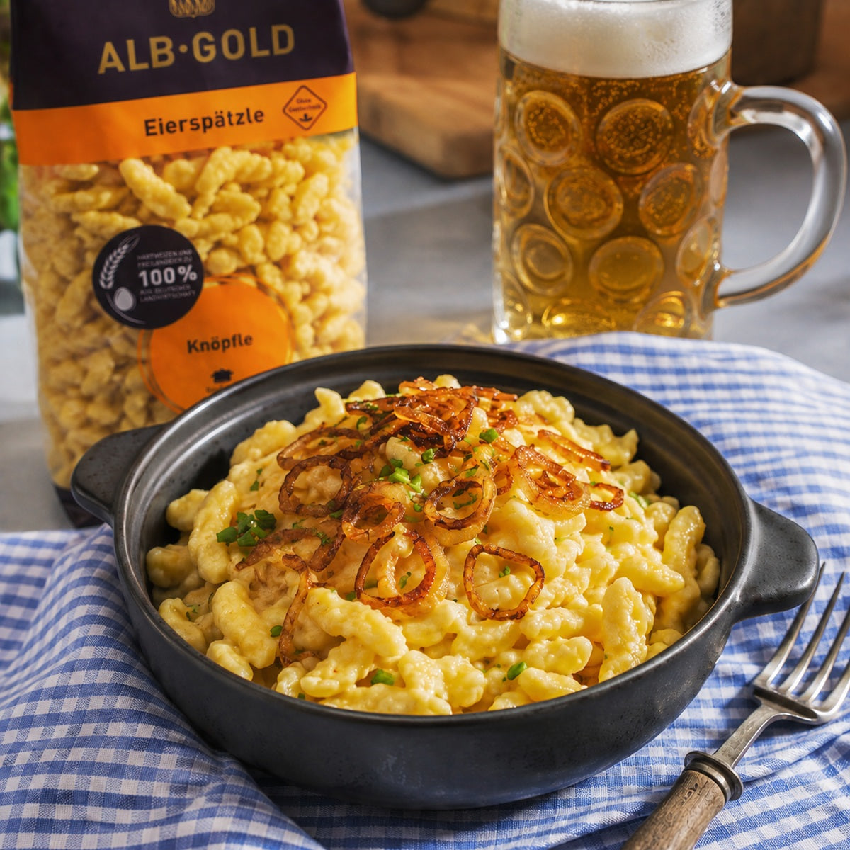 A dish of kasknopfle, amde with knopfle noodles topped with melted grated cheese and crispy fried onions.