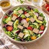 A bowl of fresh green salad with cucumber, avocado, radishes, tomatoes, mixed greens, and keto cheese crackers.