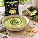 A bowl of green keto courgette soup topped with cream, chives, and peas, served with Flatland Keto Chive Crackers.