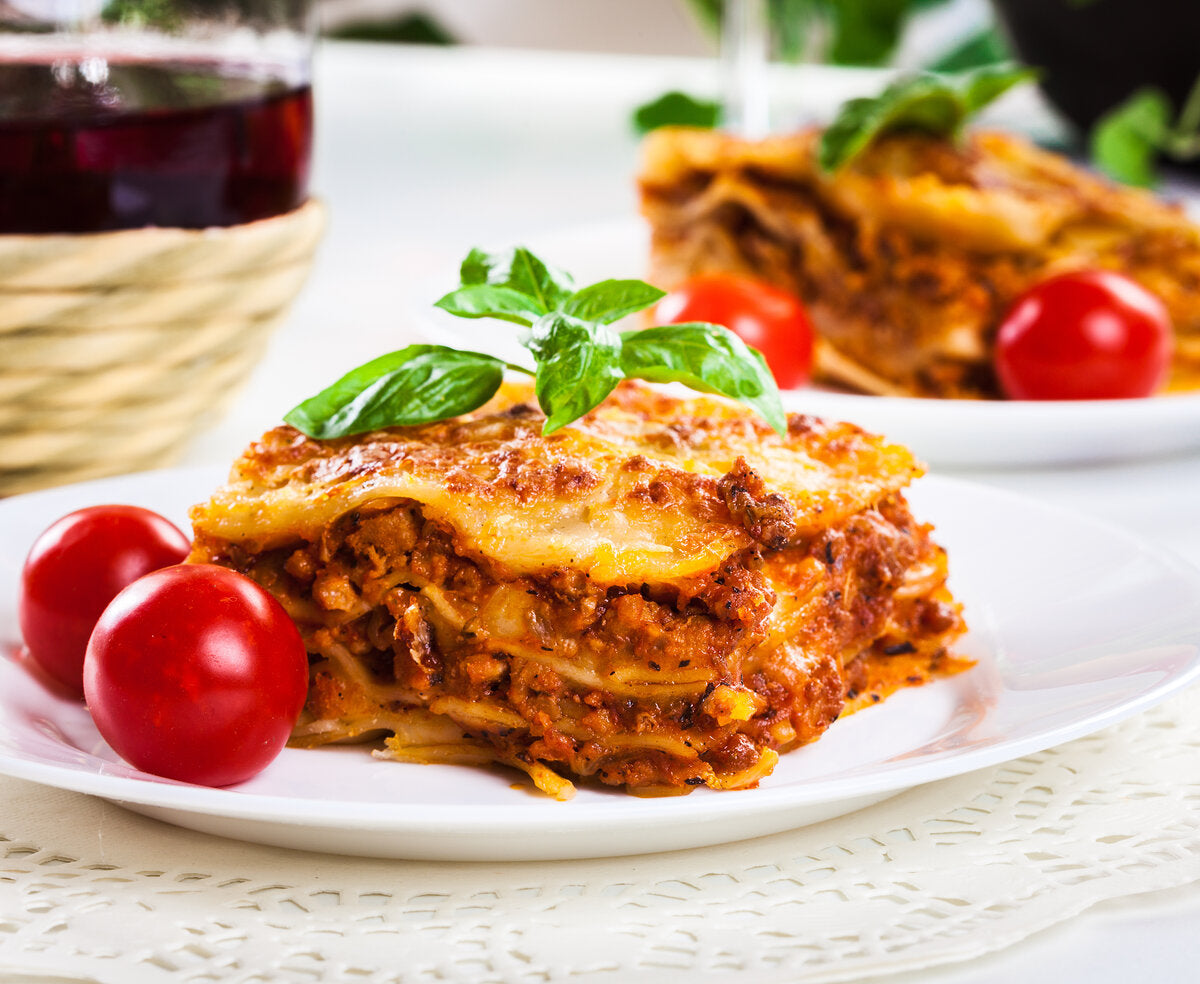 A lasagne made with tomato puree, served with basil leaves on top.