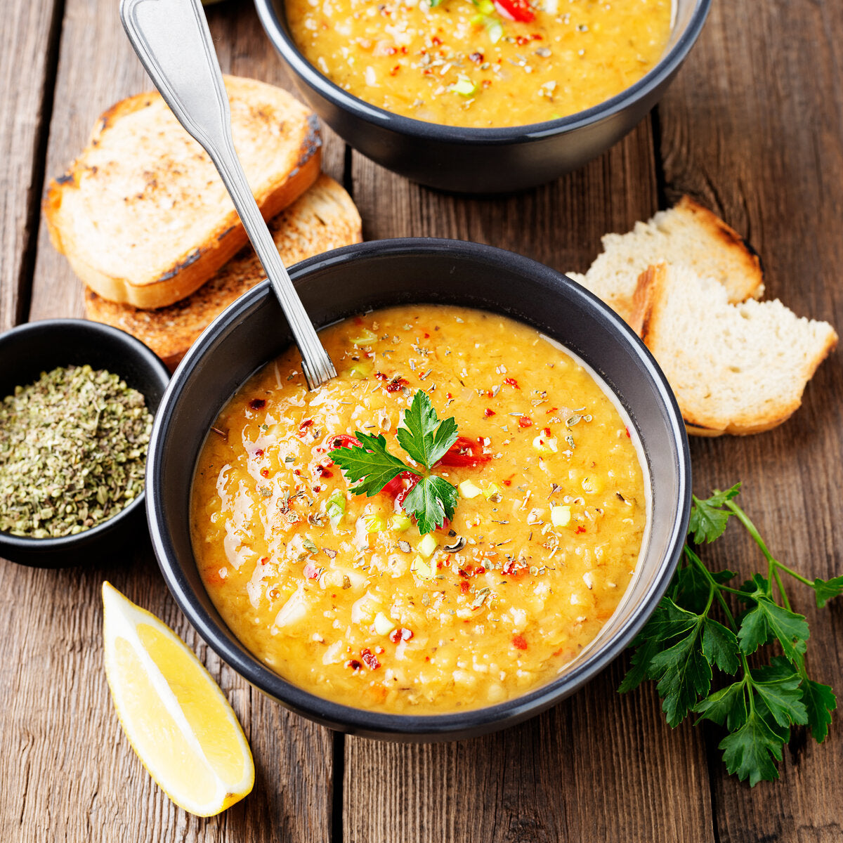 Bowl of lentil stew with dried summer savory, fresh toast and a lemon wedge.