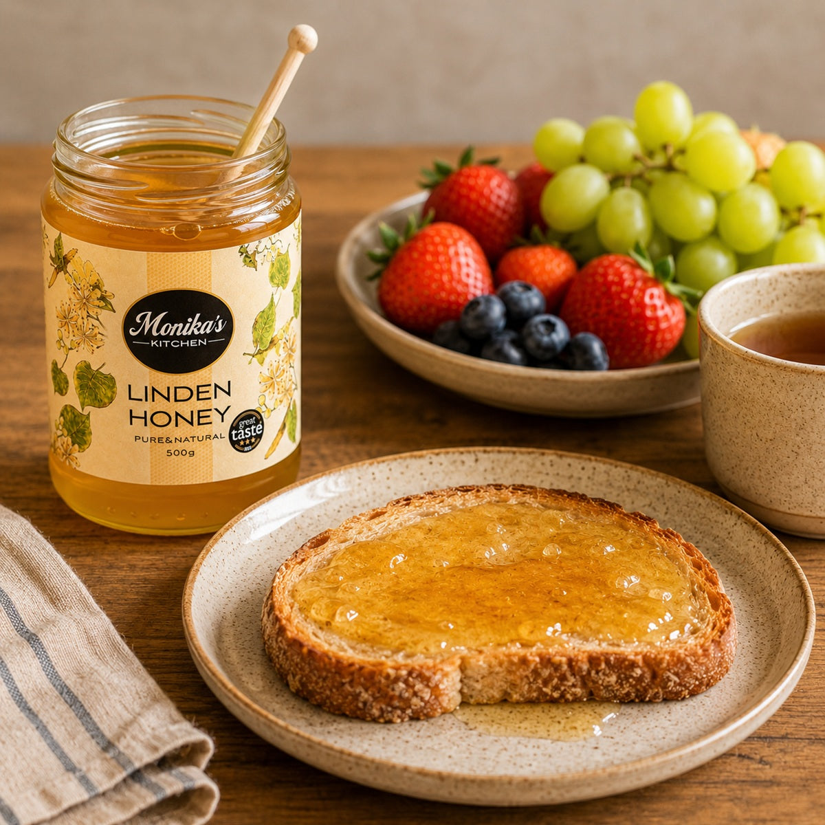 Jar of Monika's Linden Honey with toast and fruit on a wooden table